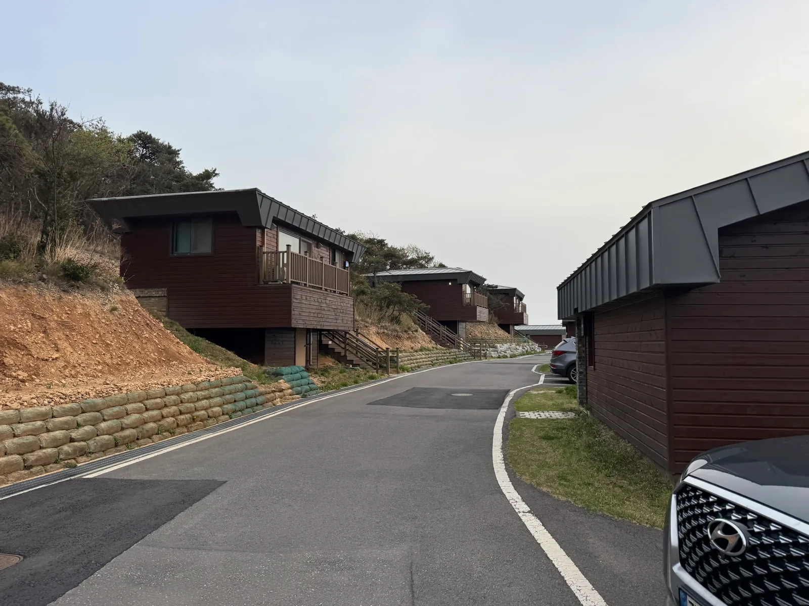 녹화 매트를 덮은 사면을 따라 목조 숙소 건물이 늘어선 진입로
