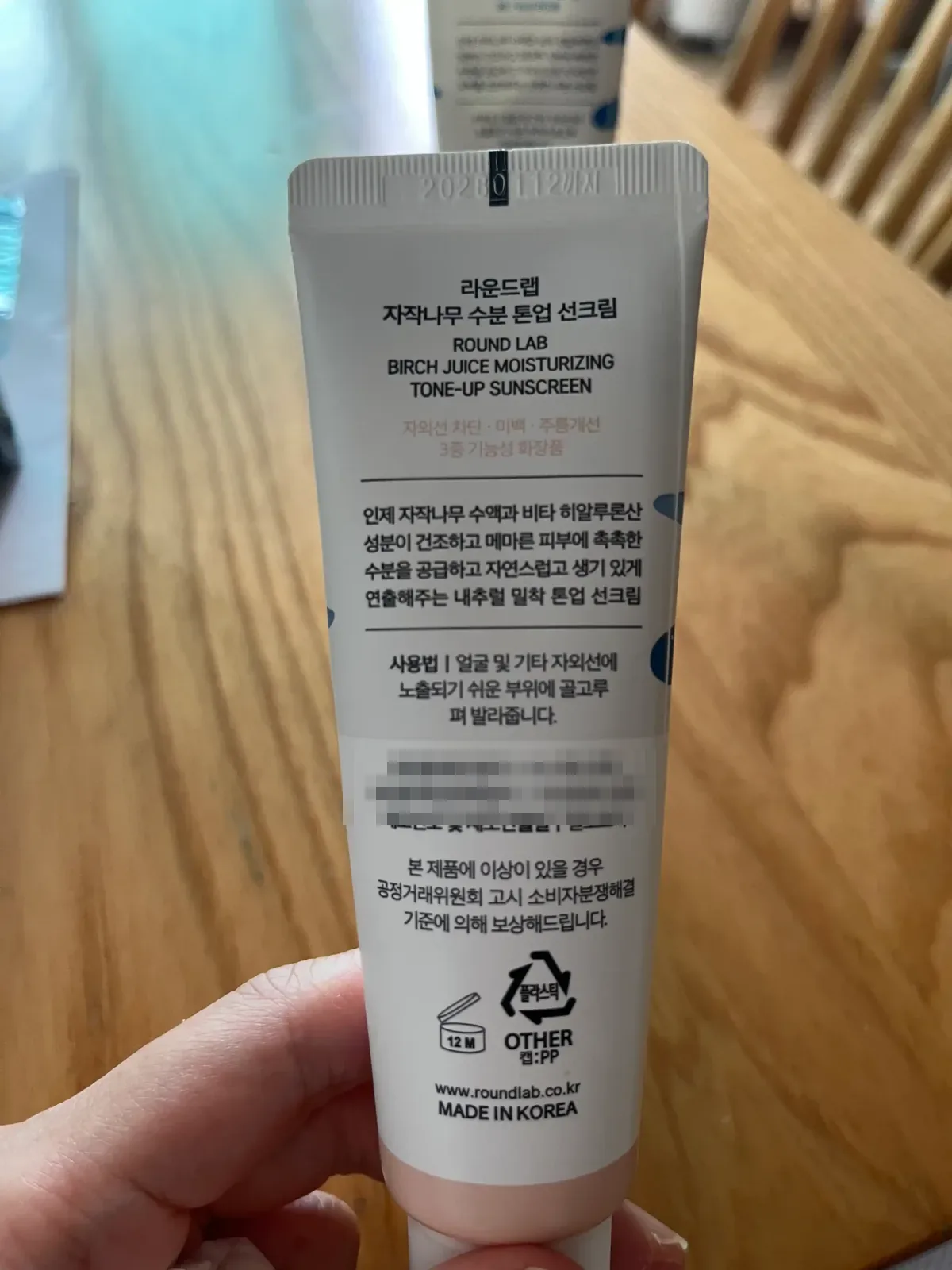 분홍색 톤업 선크림 튜브 뒷면의 굵고 선명한 제품 표기와 사용기한 인쇄